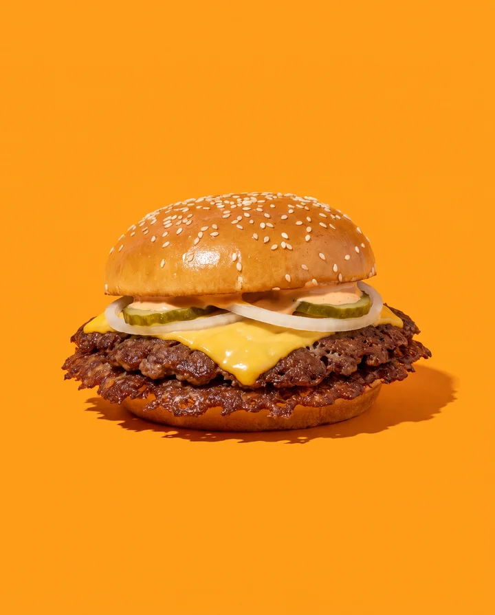 Der Platte: ein Patty mit Spitzenkruste, Käse, Zwiebel, Gurke, Sauce im Sesambrötchen.